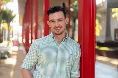 student leaning against a pole and looking toward the viewer