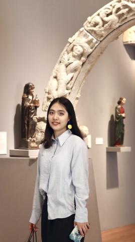 Woman in a museum gallery standing in 3/4 profile looking at the viewer