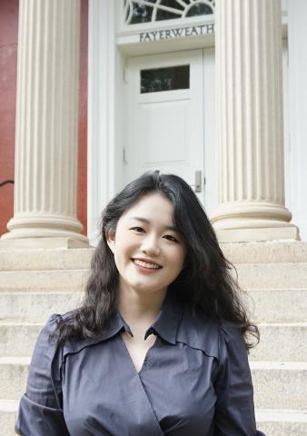young woman smiling at the camera in front of a columned porch